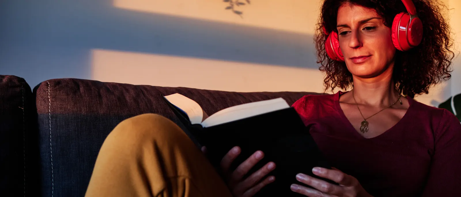 Someone reading a book in headphones by lamplight.