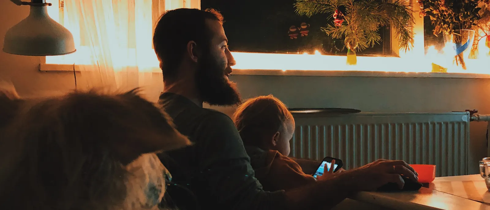A living room at dusk, lit by the screen and a single lamp.