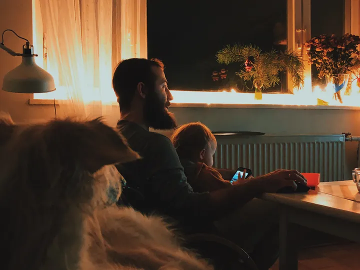 A living room at dusk, lit by the screen and a single lamp.